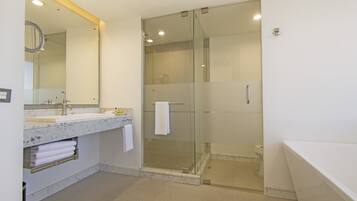 A modern bathroom with a glass-enclosed shower, a large mirror, and a white bathtub.