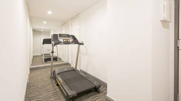 A hallway with a treadmill, carpeted floor, and a door at the end.