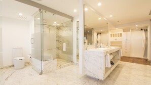 A modern bathroom with a glass-enclosed shower, a marble floor, and a large mirror. - Presidente InterContinental Guadalajara by IHG (Zapopan)