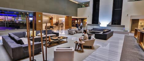 Un lobby amplio con diseño moderno, que cuenta con sofás, una mesa de centro y una zona de bar.