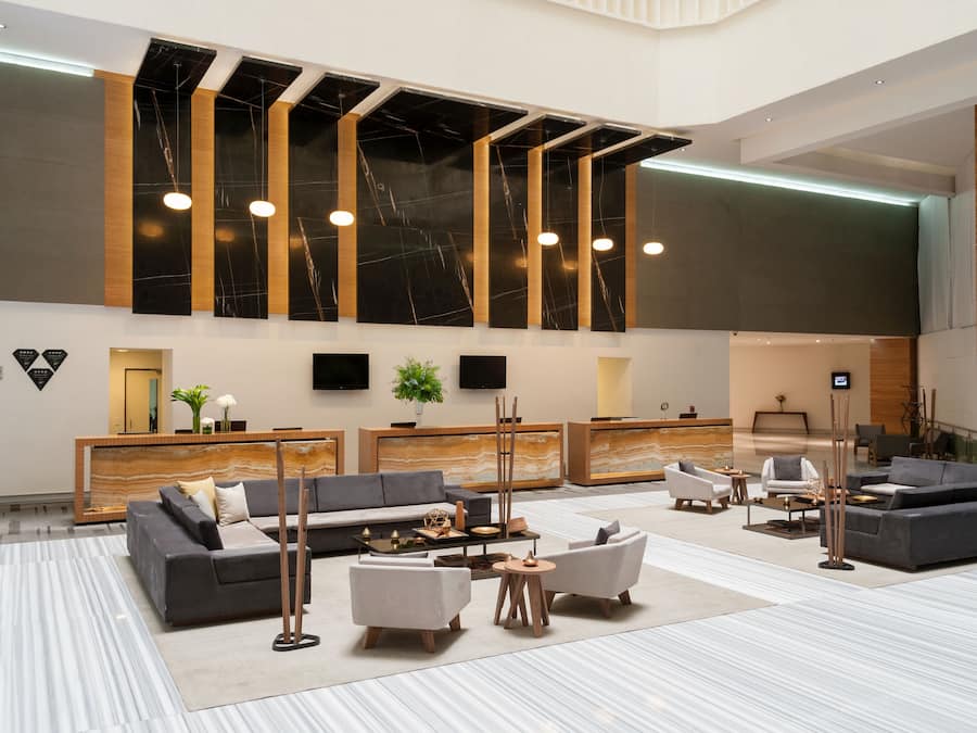 Un hall amplio con un diseño moderno, que incluye un mostrador de recepción, sofás y una zona de estar grande.