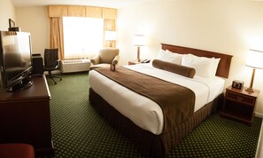 A hotel room with a large bed, a desk with a television, an air conditioning unit, and two bedside lamps. - Crowne Plaza Hotel Hickory by IHG (Hickory)