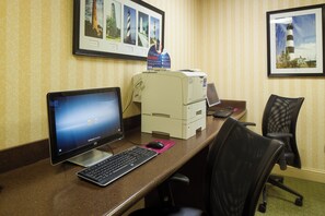 A hotel reception desk with a desktop computer, a printer, and framed pictures on the wall. - Crowne Plaza Hotel Hickory by IHG (Hickory)