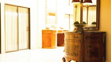 A hallway with a wooden cabinet and a mirror reflecting a lamp.