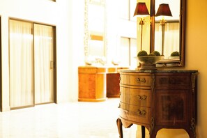 A hallway with a wooden cabinet and a mirror reflecting a lamp. - Crowne Plaza Hotel Hickory by IHG (Hickory)