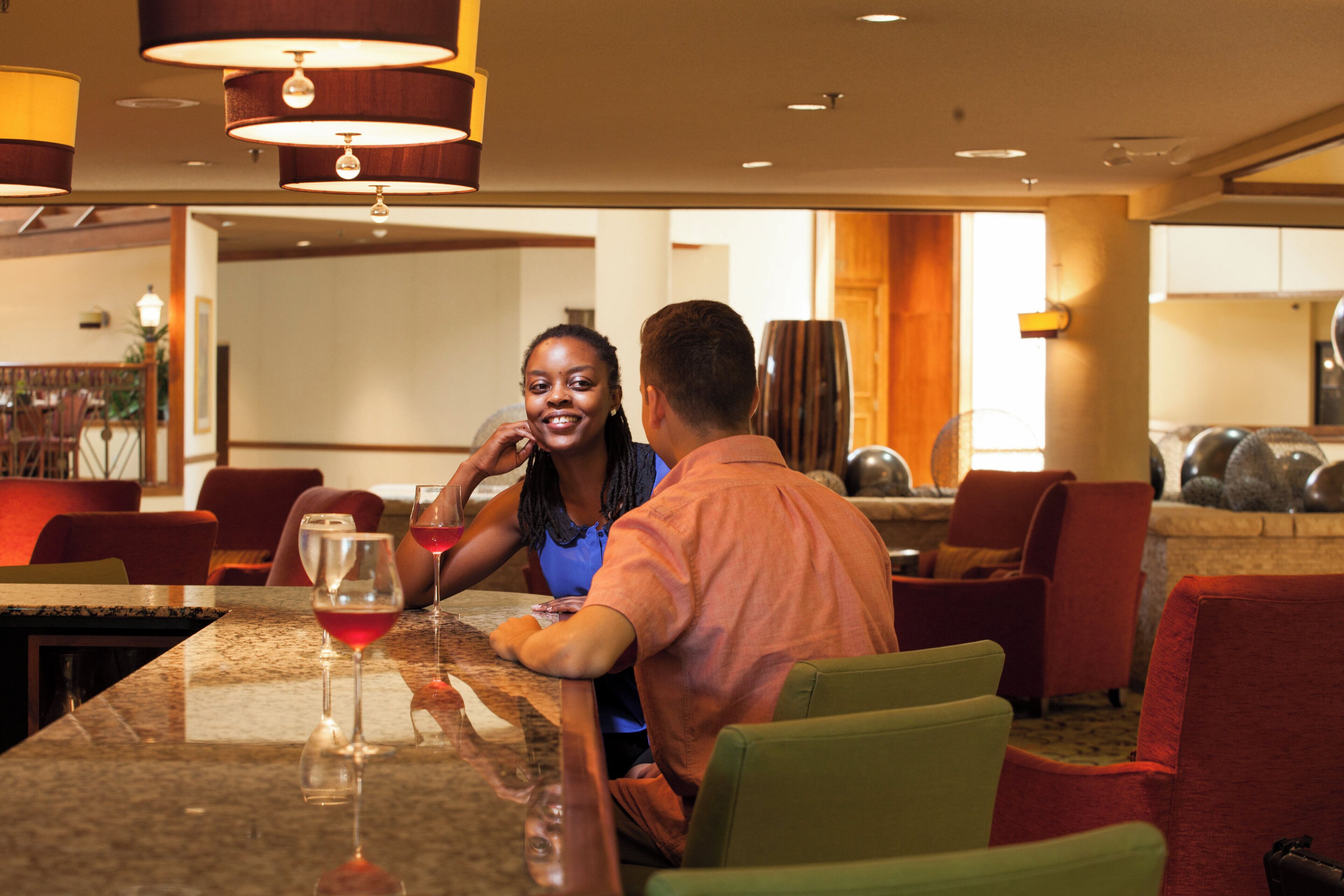 A hotel dining area with a marble table, red chairs, and a view of the lobby.