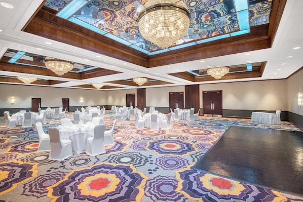 A spacious banquet hall with a patterned carpet, multiple tables set for events, and ornate chandeliers. - Crowne Plaza Hotel Hickory by IHG (Hickory)