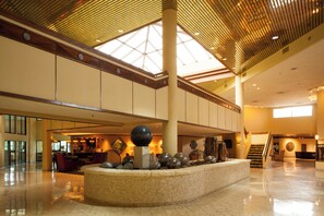 A spacious lobby with a high ceiling, a central decorative feature, and a staircase leading to an upper level. - Crowne Plaza Hotel Hickory by IHG (Hickory)