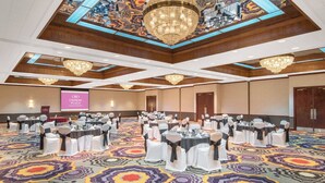 A conference room with round tables, white chairs, and a large chandelier. - Crowne Plaza Hotel Hickory by IHG (Hickory)