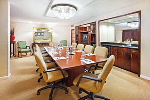 A conference room with a long table, chairs, a television, and a kitchen area. - Crowne Plaza Hotel Hickory by IHG (Hickory)