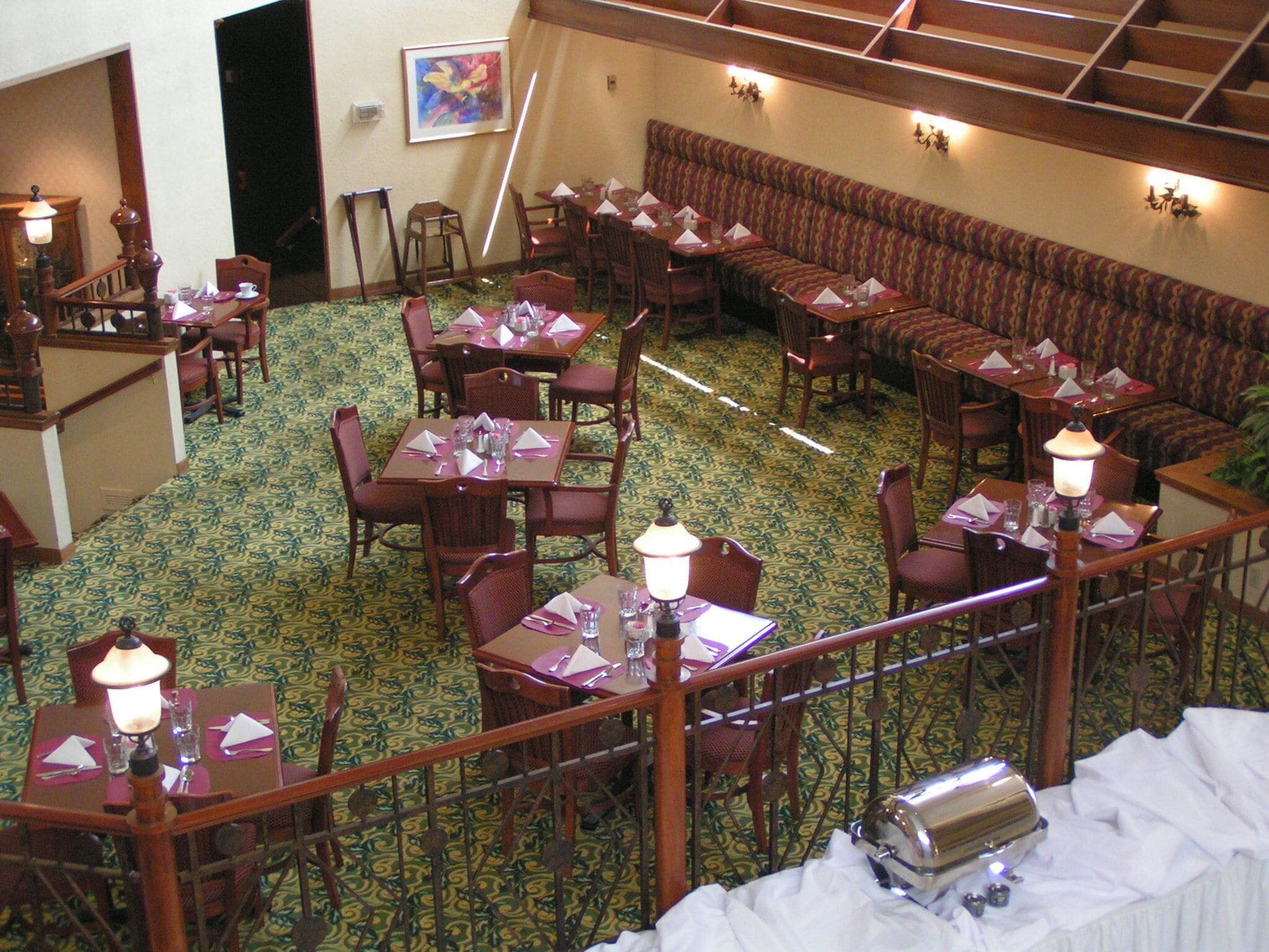 A dining area with multiple tables and chairs, a patterned carpet, and a staircase.