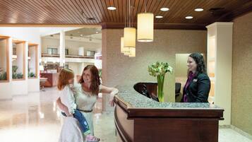 A reception desk in a hotel lobby with a modern design, including a wooden ceiling and pendant lighting.