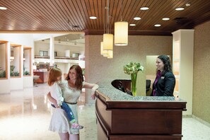 A reception desk in a hotel lobby with a modern design, including a wooden ceiling and pendant lighting. - Crowne Plaza Hotel Hickory by IHG (Hickory)