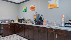 A kitchen with a granite countertop, wooden cabinets, and various appliances like a waffle maker and coffee maker.
