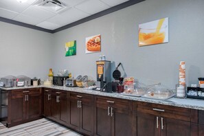 A kitchen with a granite countertop, wooden cabinets, and various appliances like a waffle maker and coffee maker.