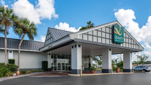 A hotel with a covered entrance, palm trees, and a clear sky.
