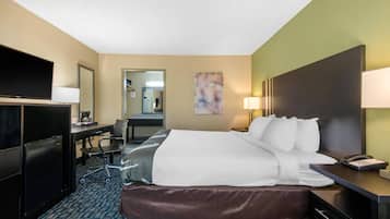 Habitación de hotel con cama, escritorio, silla, televisor y espejo.