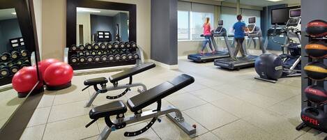 A gym with treadmills, weight benches, and exercise balls.
