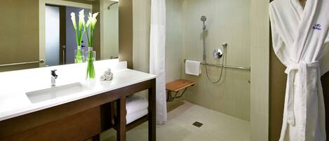 A modern bathroom with a large sink, mirror, and shower area.