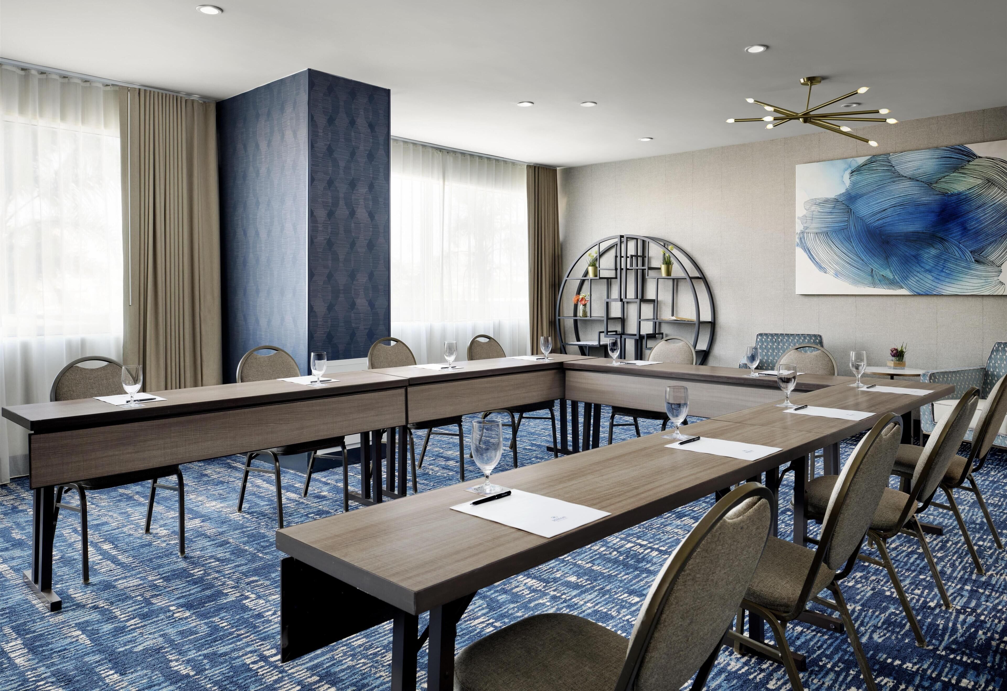 A conference room with a long table, chairs, and a bookshelf.
