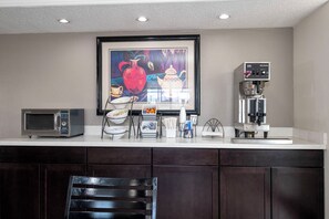 Una cocina con microondas industrial, máquina de café y un cuadro enmarcado sobre la encimera.