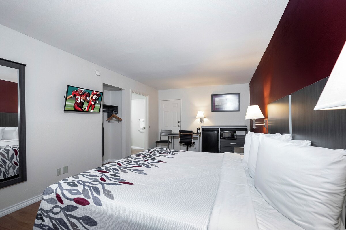 Een hotelkamer met een groot bed, een bureau met stoel, een televisie en een magnetron.