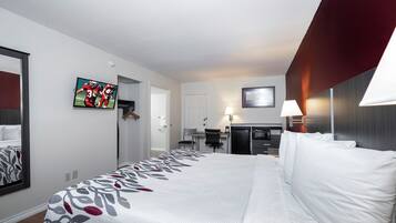 Quarto de hotel com uma cama grande, uma escrivaninha com cadeira, televisão e micro-ondas.