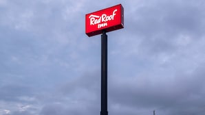 A Red Roof Inn with a two-story building, a red roof, and a signboard.
