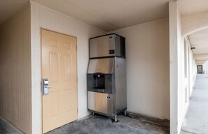 A hallway with a door and a stainless steel refrigerator. - Red Roof Inn Houston North - FM 1960 & I-45 (Houston)