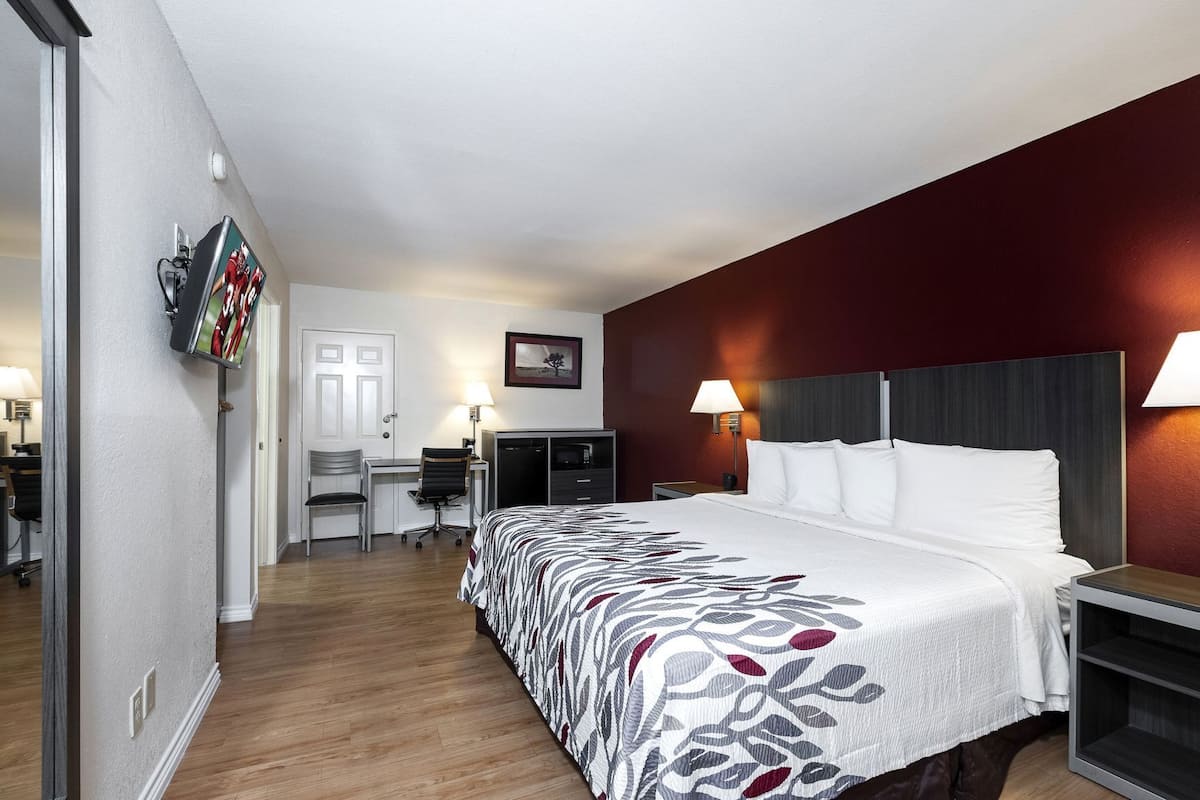 A hotel room with a bed, desk, chair, and two lamps.