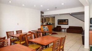 A dining area with wooden tables and chairs, a reception desk, and a staircase leading to another level. - Knights Inn Gallup at 3208 W Hwy 66 (Gallup)