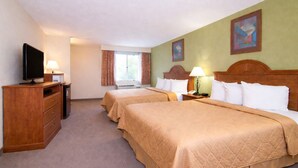 A hotel room with two beds, a TV, a desk with a lamp, and a window with curtains. - Knights Inn Gallup at 3208 W Hwy 66 (Gallup)