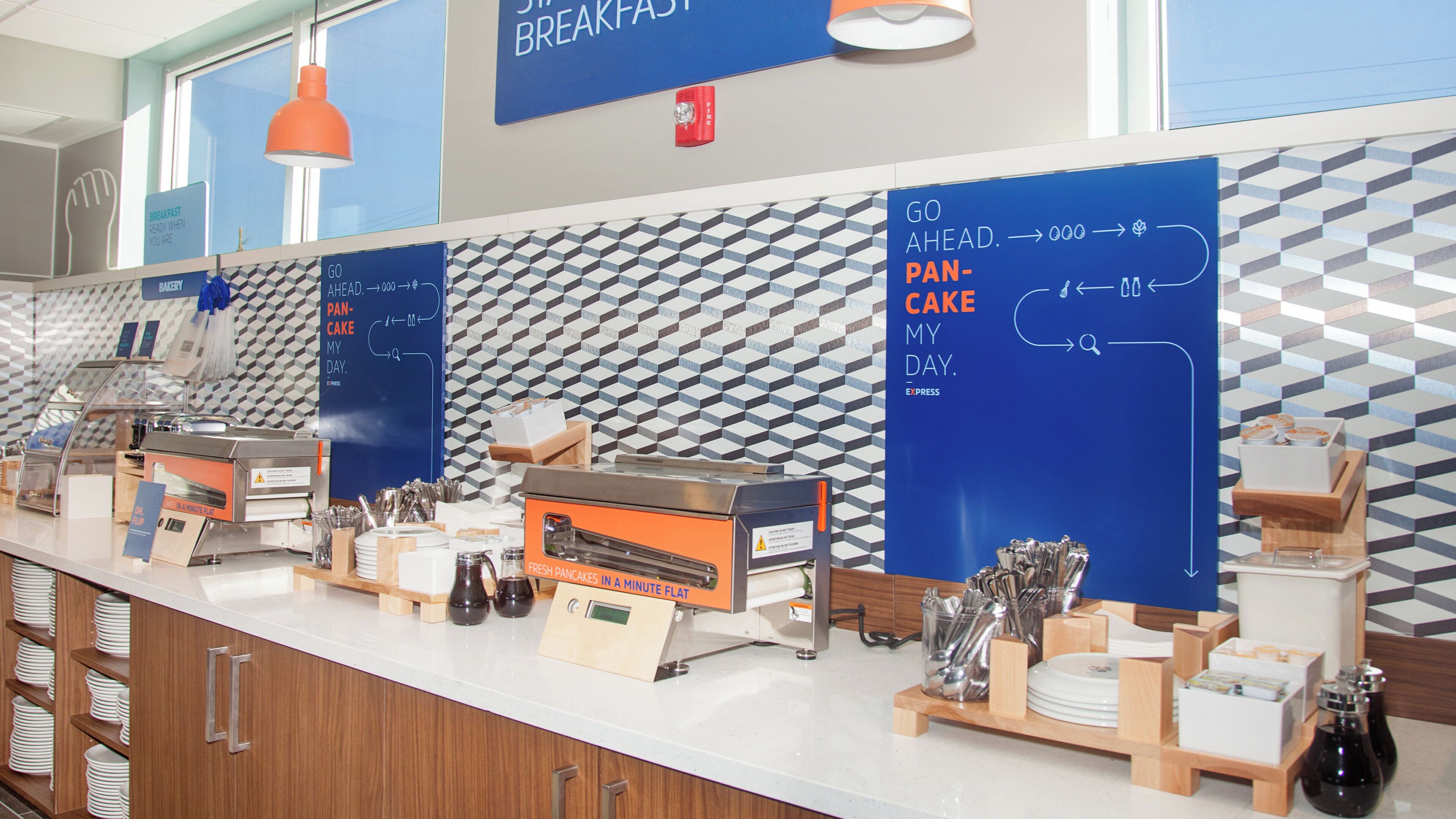 A breakfast counter with signage for a bakery and pan-cake, a fresh pancakes machine, and a variety of breakfast items.