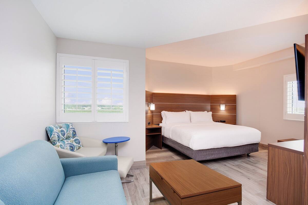 Une chambre d’hôtel avec un lit, un canapé, une petite table et un téléviseur.