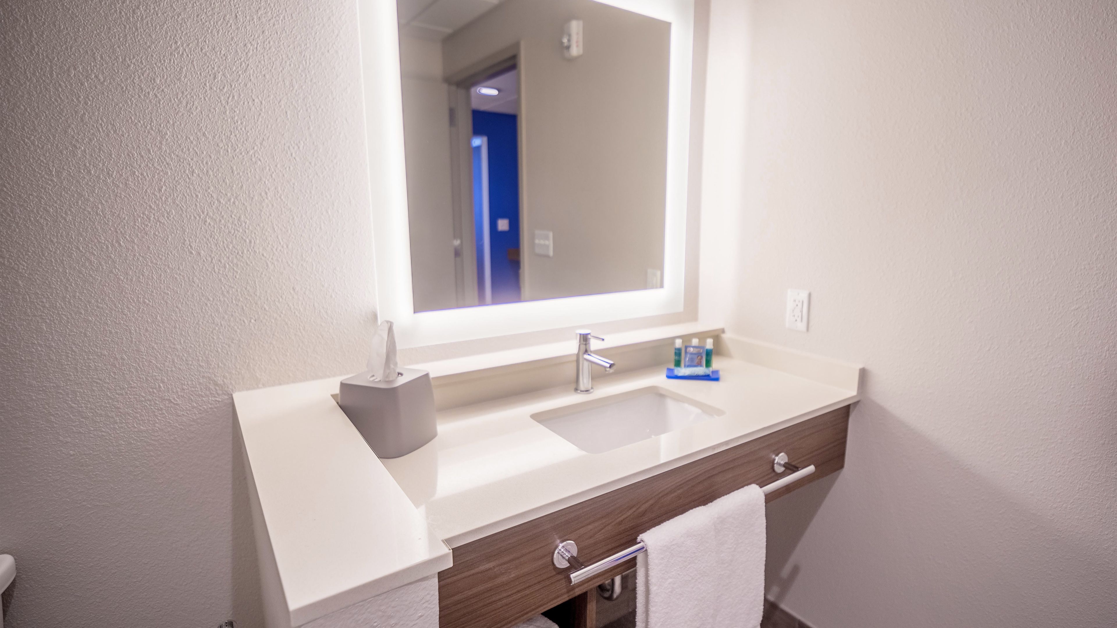Une salle de bain moderne avec un lavabo blanc, un miroir et un porte-serviettes.