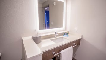 A modern bathroom with a white sink, a mirror, and a towel rack.