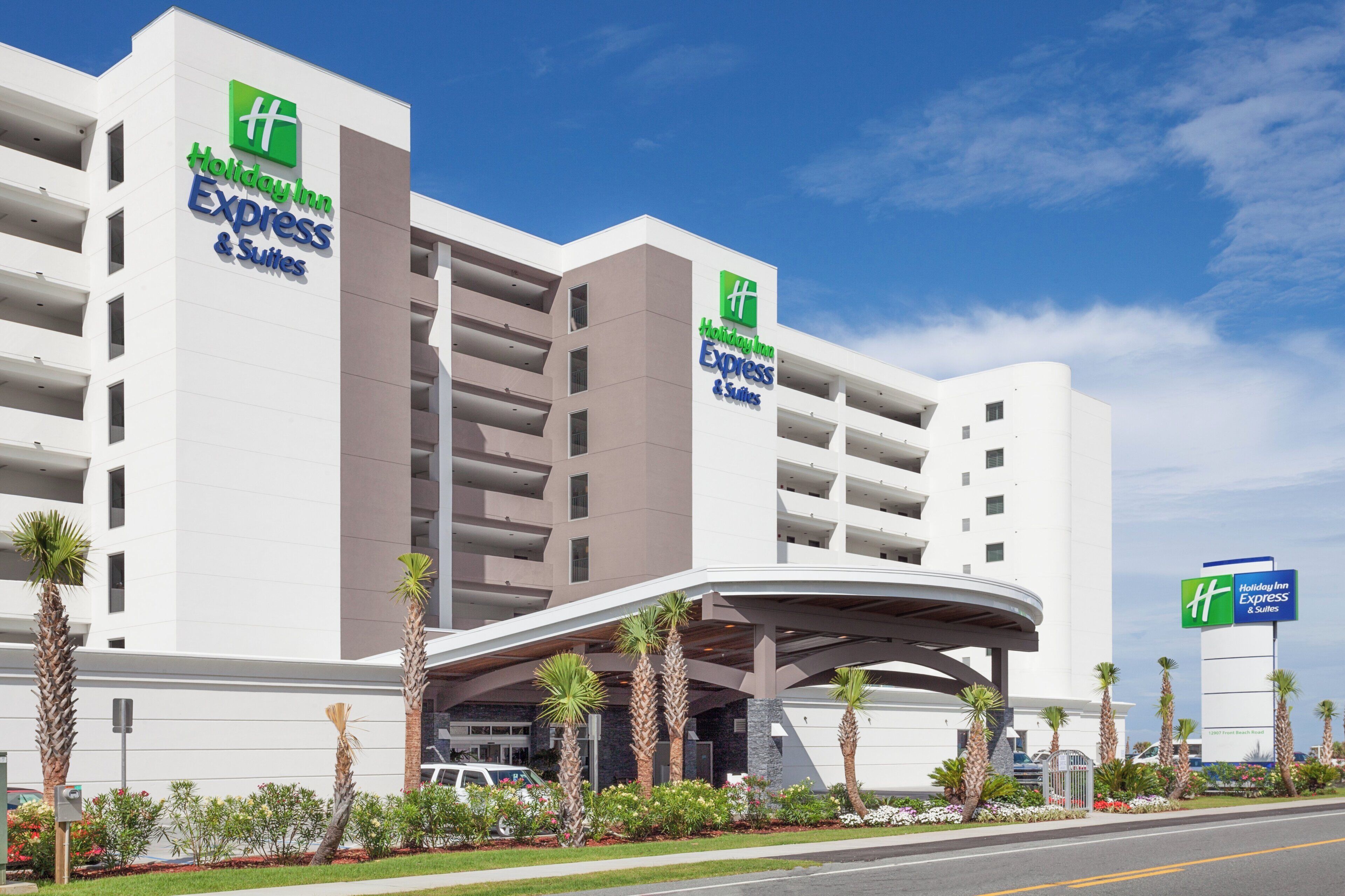 Edificio de Holiday Inn Express & Suites con un diseño arquitectónico moderno, que presenta una entrada destacada y un área de estacionamiento.