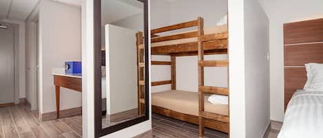 Habitación de hotel con literas, un escritorio y un espejo grande.