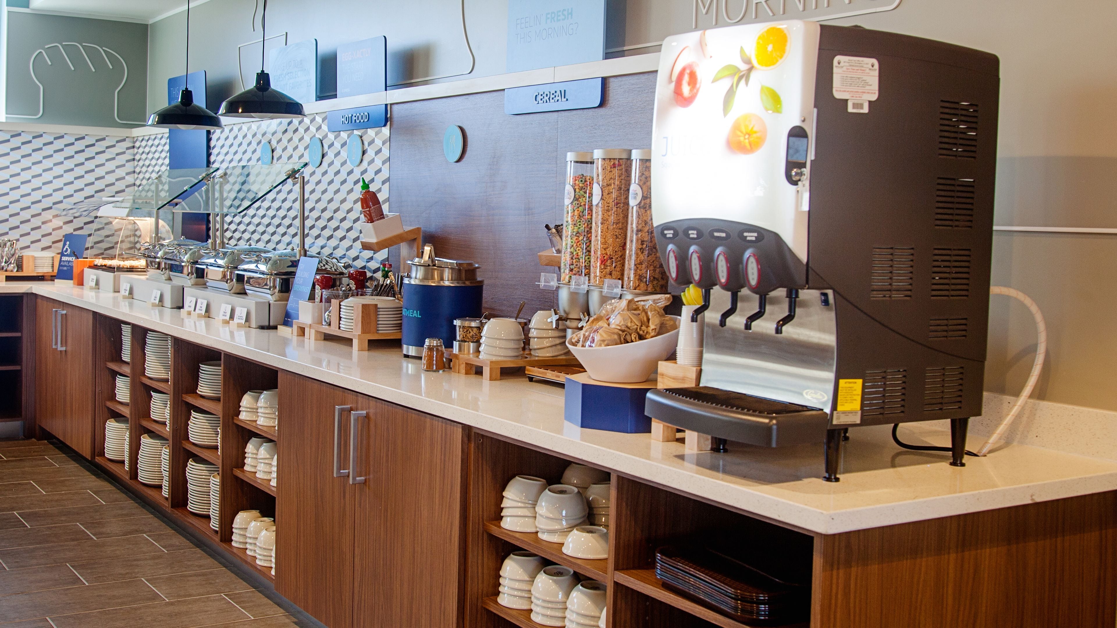 A breakfast bar with a coffee machine, cereal dispensers, and a fruit display.