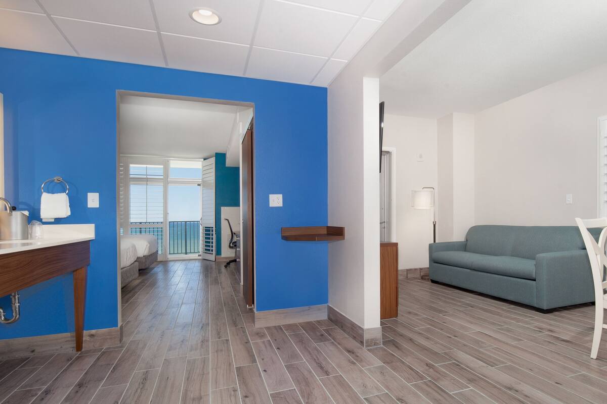 Un salon moderne avec un mur d’accent bleu, un canapé gris et un ensemble de salle à manger blanc.