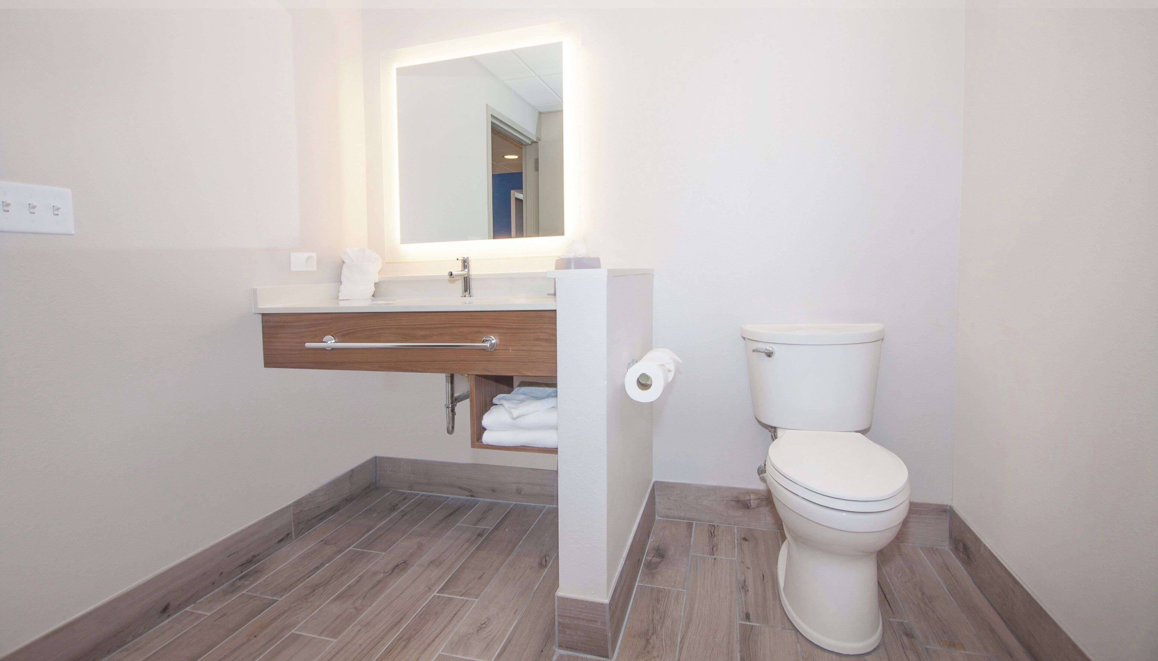 A bathroom with a toilet, a sink with a mirror, and a towel rack.
