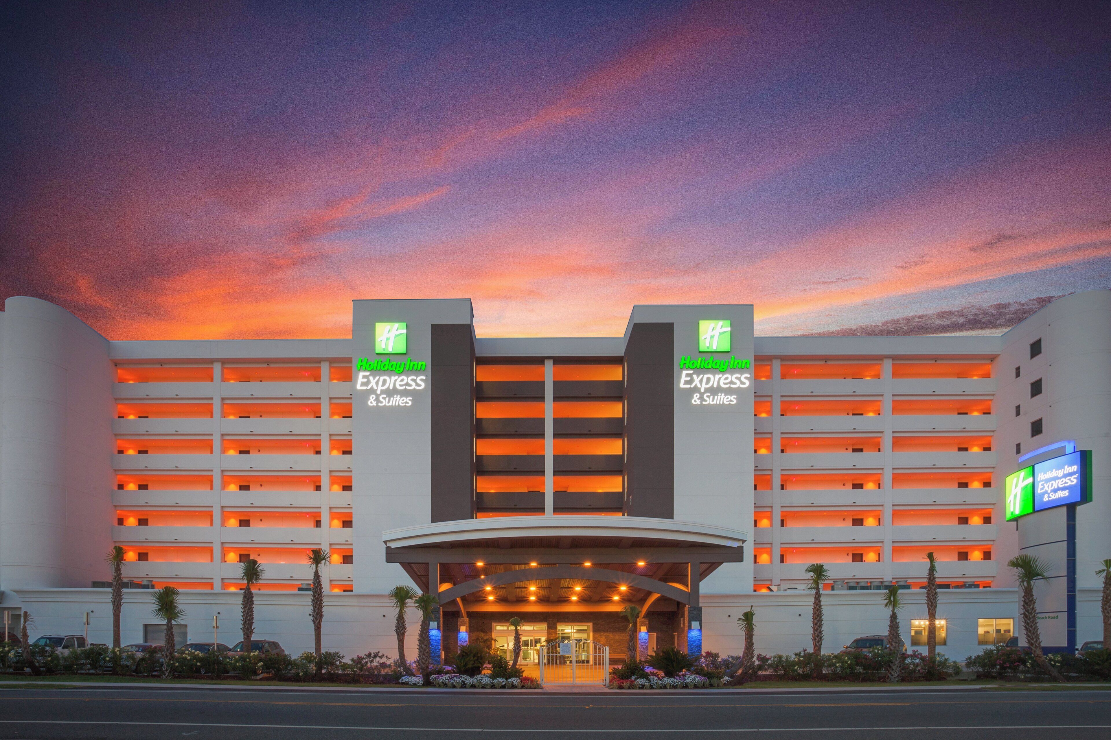 Ett Holiday Inn Express & Suites-hotell med modern design, kännetecknat av en stor entré och flera våningar.