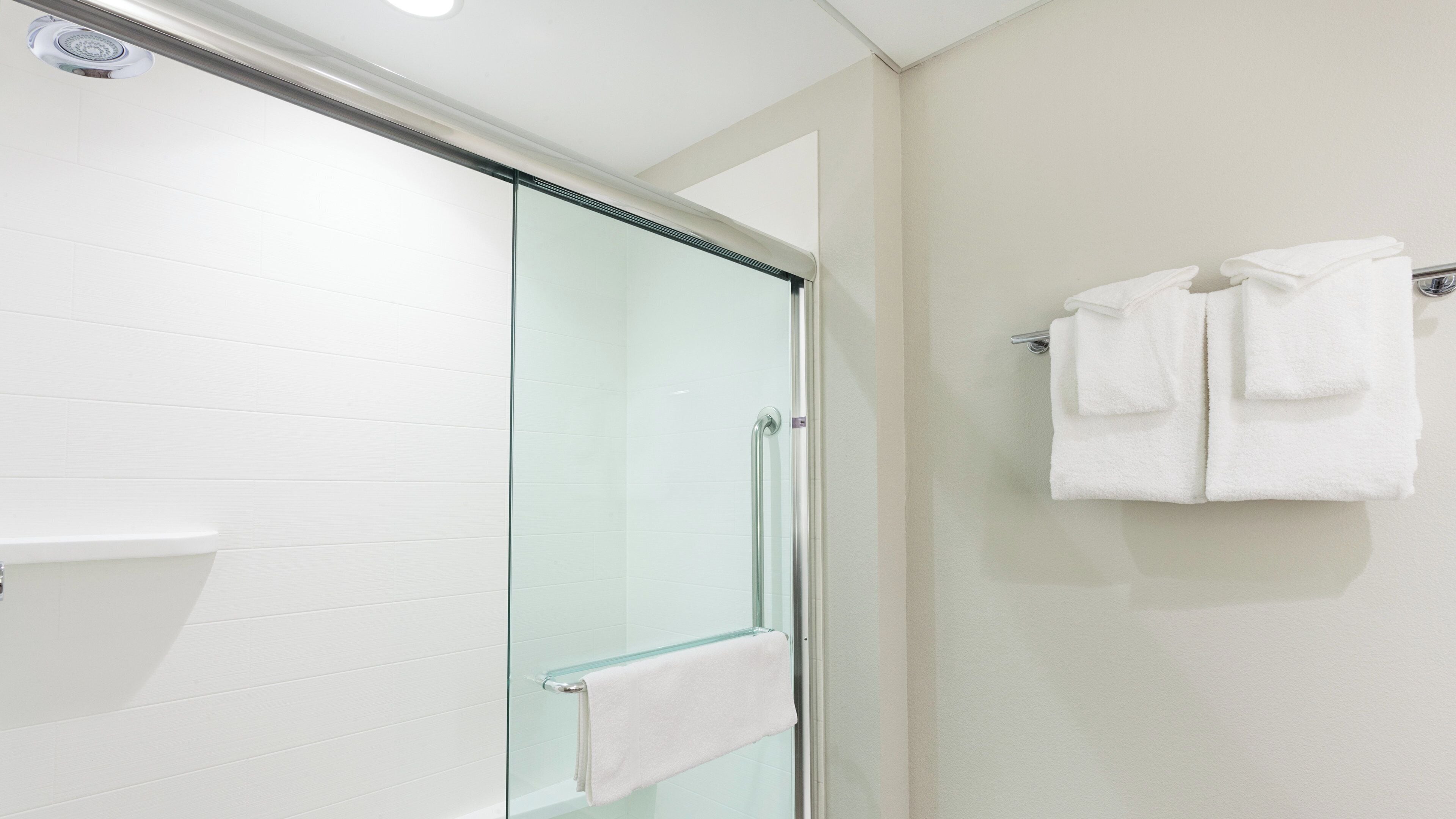 A modern bathroom with a glass shower enclosure, a white towel rack, and a white tiled wall.