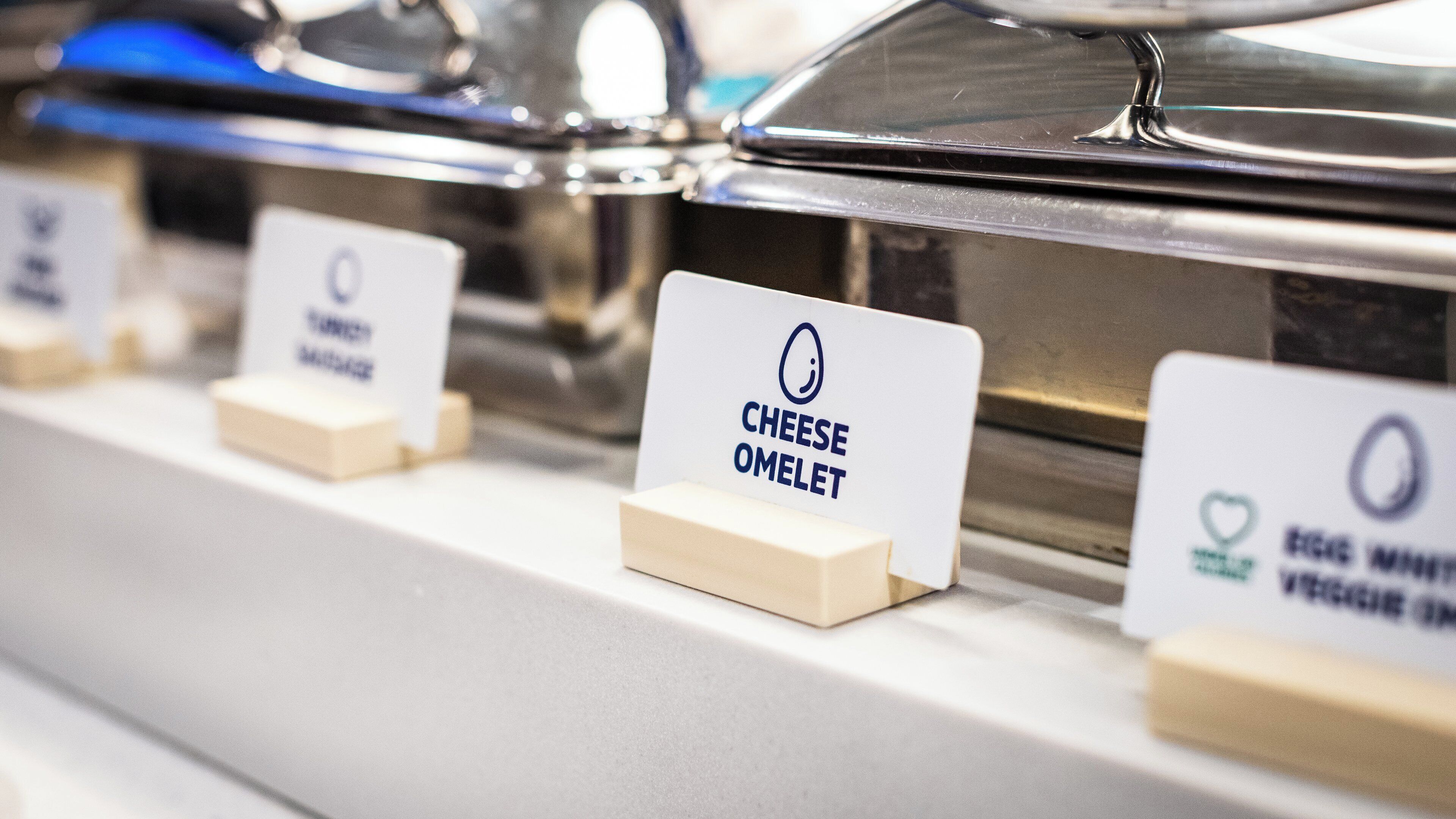 Un bufé de desayuno con secciones identificadas para distintos tipos de alimentos.