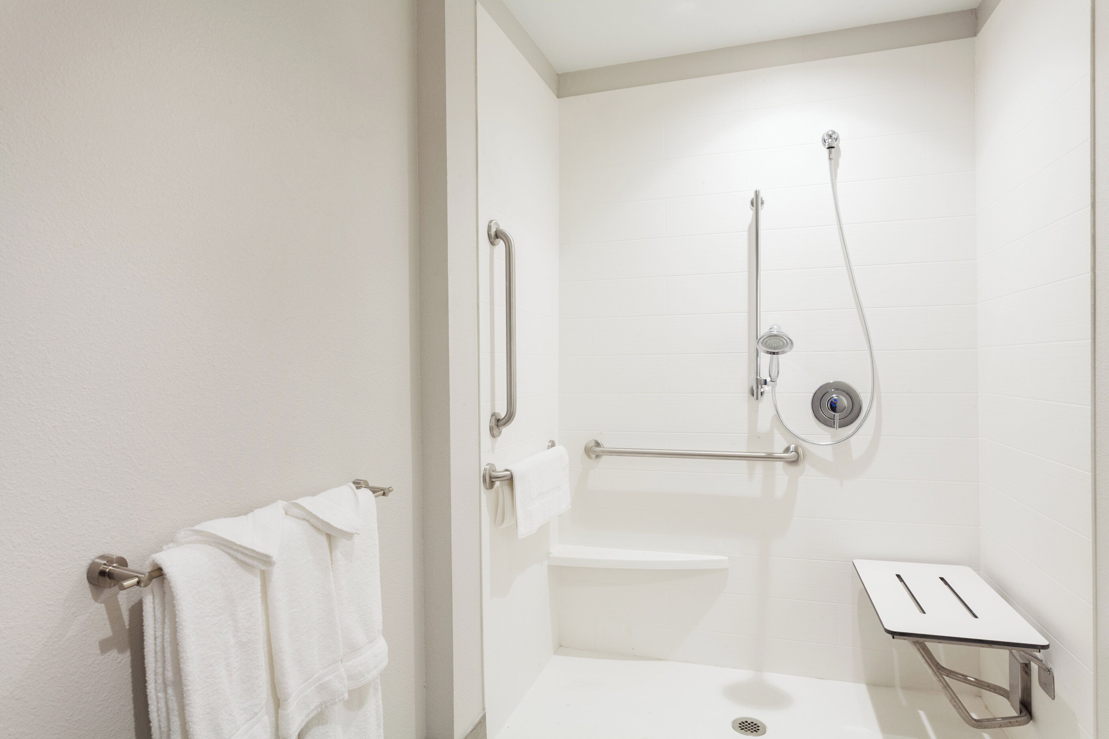 Un baño con ducha, inodoro y perchero para toallas.