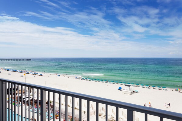 A beach view with a pier, a pool area, and beach umbrellas. - Holiday Inn Express & Suites Panama City Beach - Beachfront by IHG (Panama City Beach)