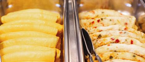 A buffet with yellow and white food items, including what appears to be fried bananas and stuffed pastries.
