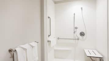 A modern bathroom with a shower, grab bars, and a towel rack.
