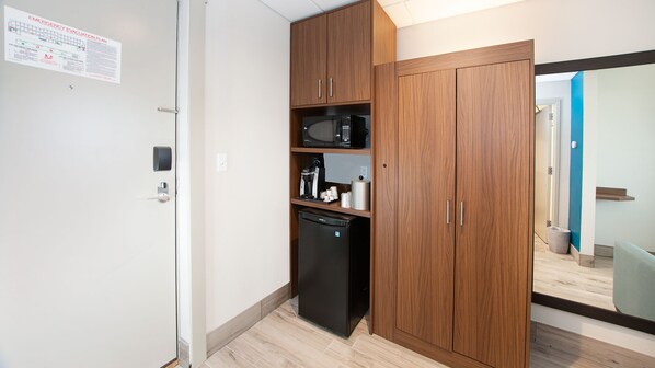 Una kitchenette compacta con microondas, cafetera y refrigerador.