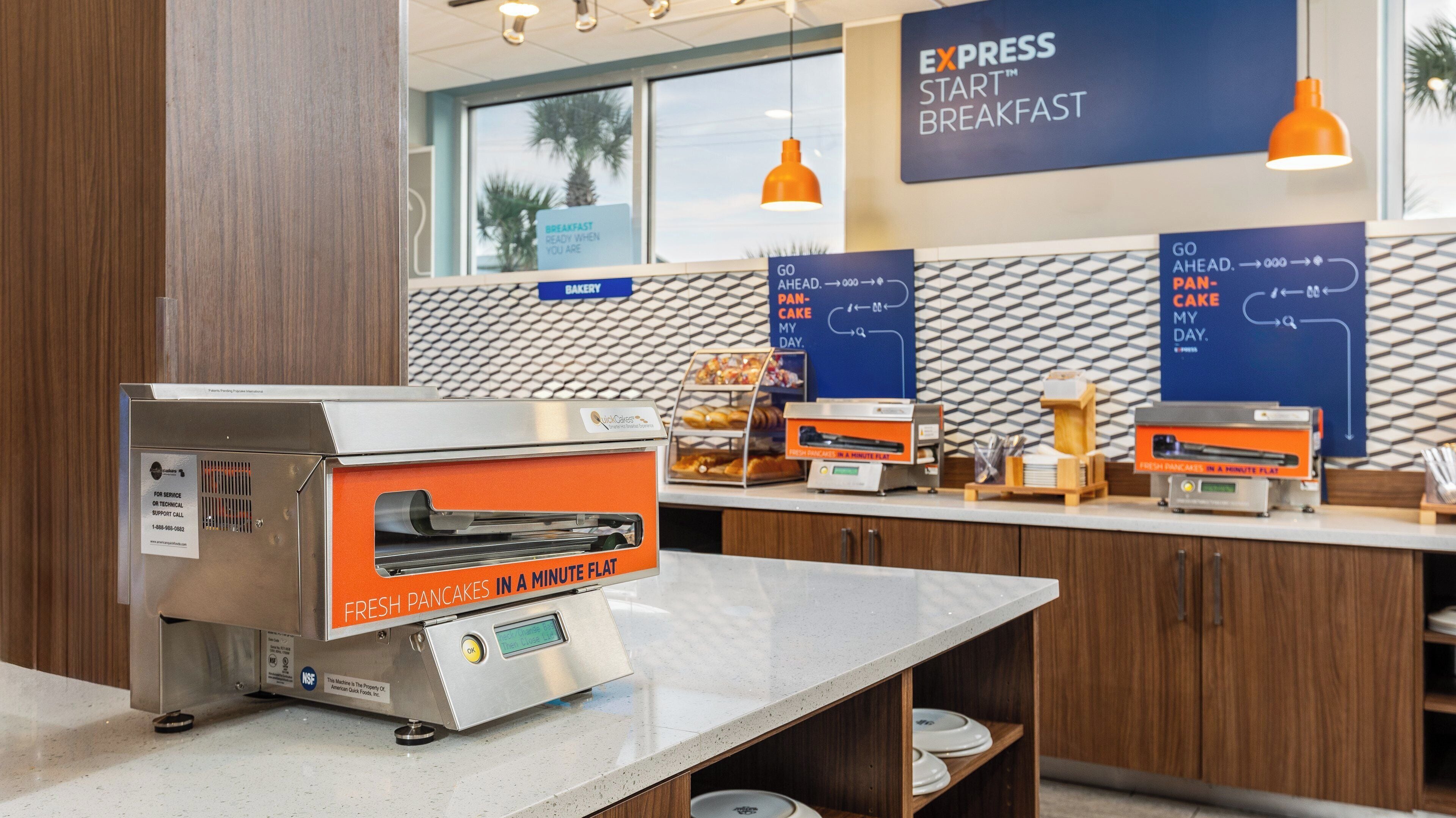 A breakfast area with a QuickEats machine for fresh pancakes, bakery display, and directional signs for breakfast and pan-cake.